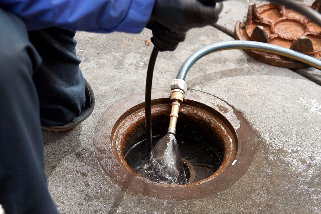 Plumber hydro jetting a sewer line through a manhole in Daytona Beach
