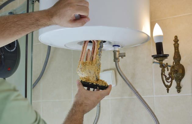 Technician removing mineral buildup from a water heater in Daytona Beach
